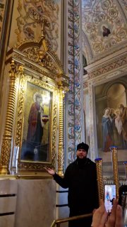 Митрополит Никандр в интерьере храма у иконы «Боголюбская»: кадр из пресс‑тура показывает священнослужителя на фоне росписей и икон.