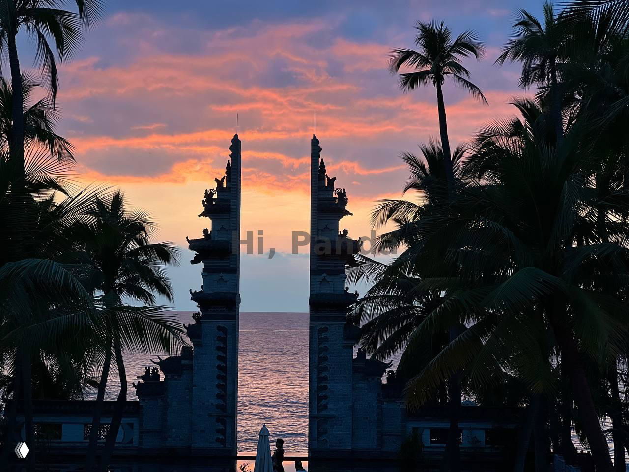 Вид на морской пейзаж через декоративные ворота и пальмы при ярком розово-оранжевом небе на закате, силуэт человека у перил.