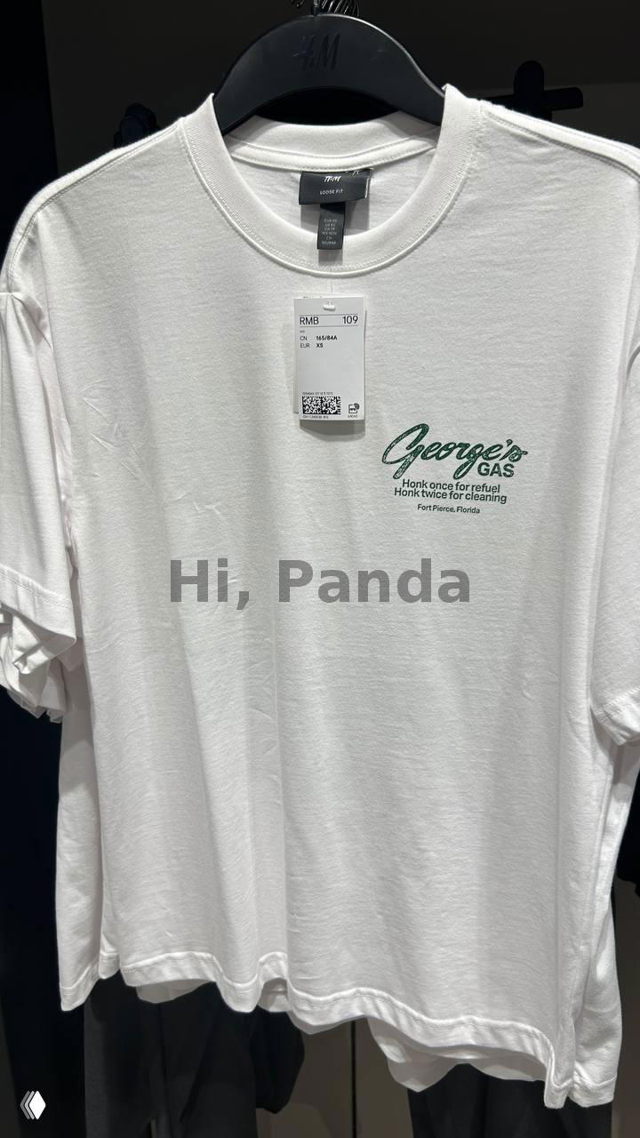 Белая футболка H&M с небольшим зелёным логотипом и биркой, видно ценник и часть торгового зала в ТЦ Mangrove Tree Sanya.