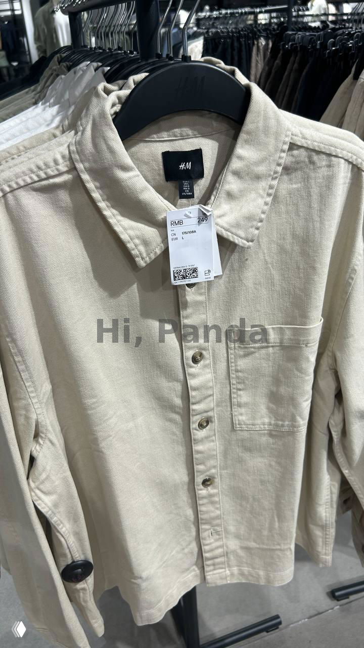 Крупный план бежевой рубашки H&M: лейбл, бирка и текстура ткани хорошо видны, фотография сделана внутри магазина в ТЦ Mangrove Tree Sanya.