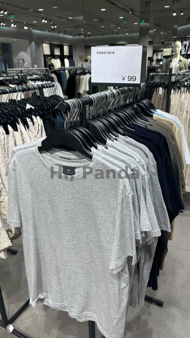 Стойка с серыми футболками H&M и табличкой с ценой ¥99, видно зеркала и оформление торгового зала в ТЦ Mangrove Tree Sanya.