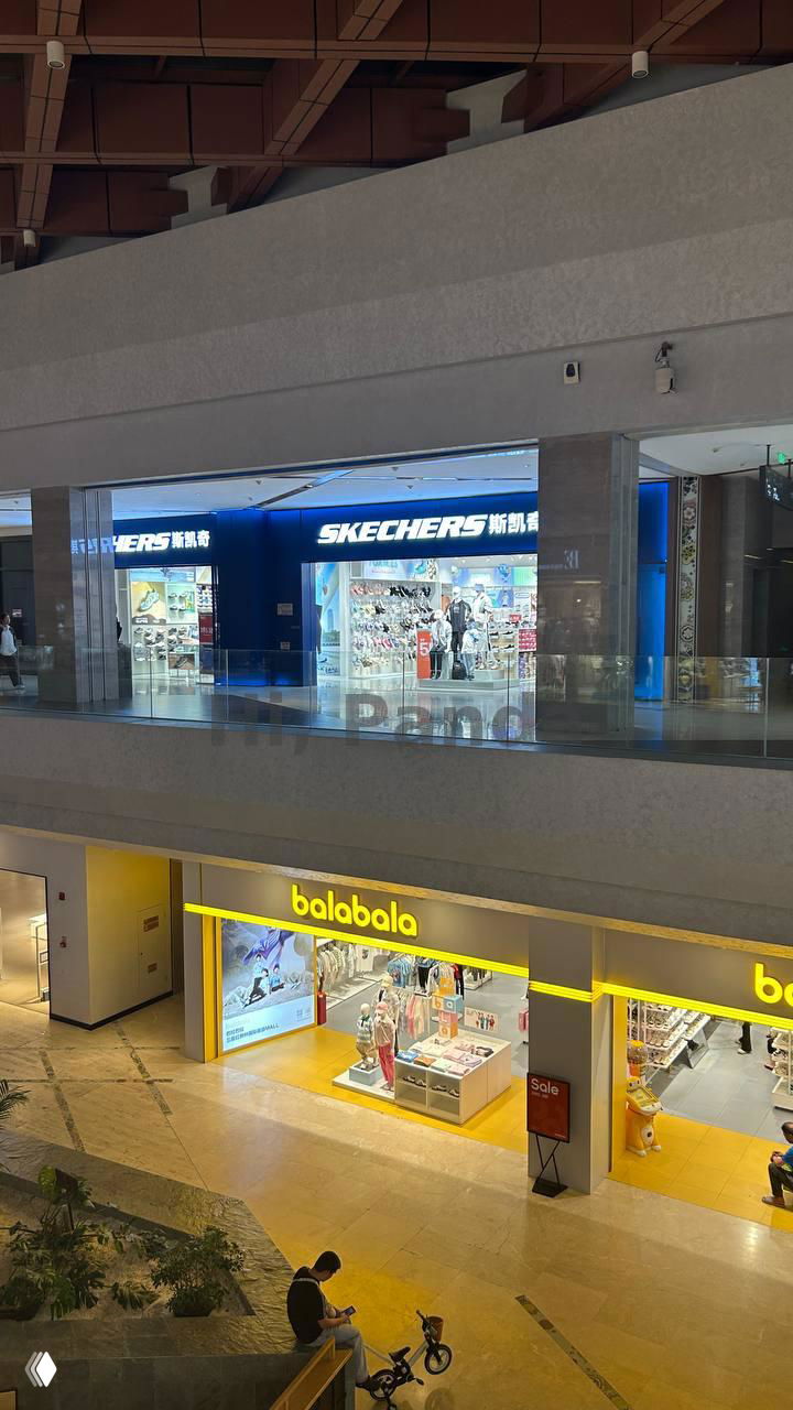 Вид с галереи на второй этаж с магазинами Skechers и Balabala, обзор на атриум торгового центра с витринами и покупателями внизу.