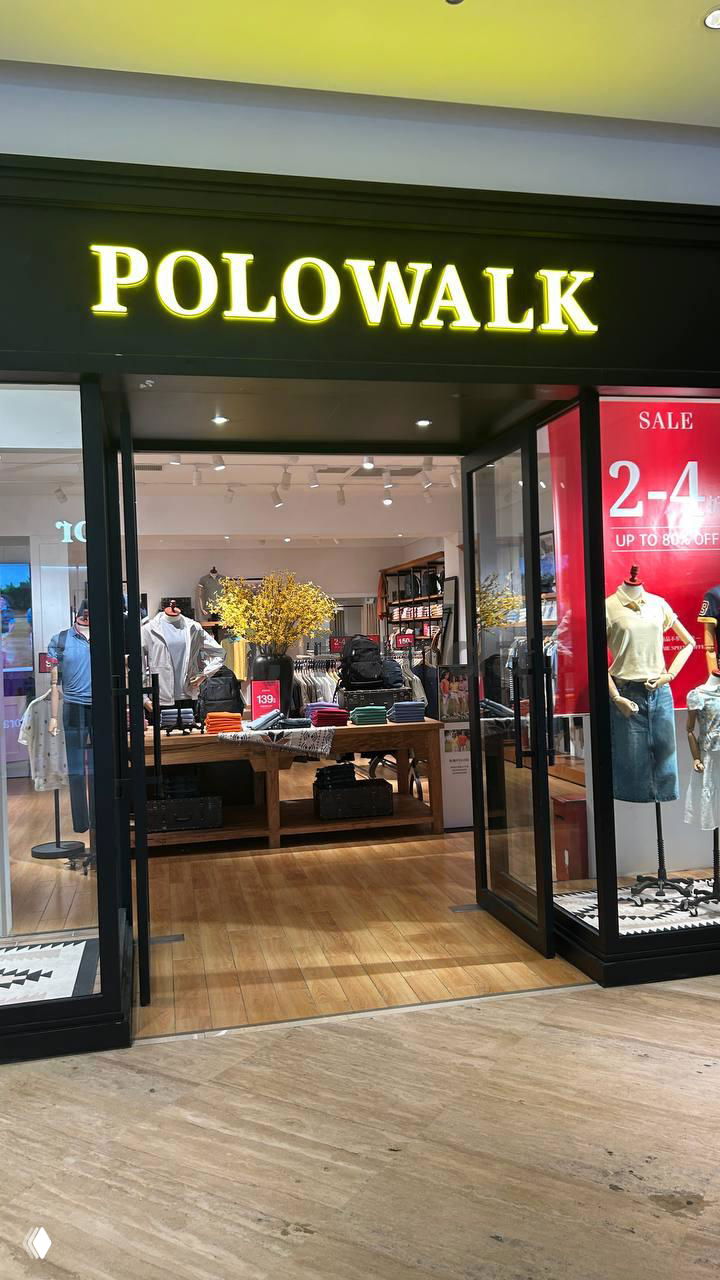 Вход Polowalk с деревянным полом и витринами, на которых размещены сезонные предложения и рекламные таблички со скидками.