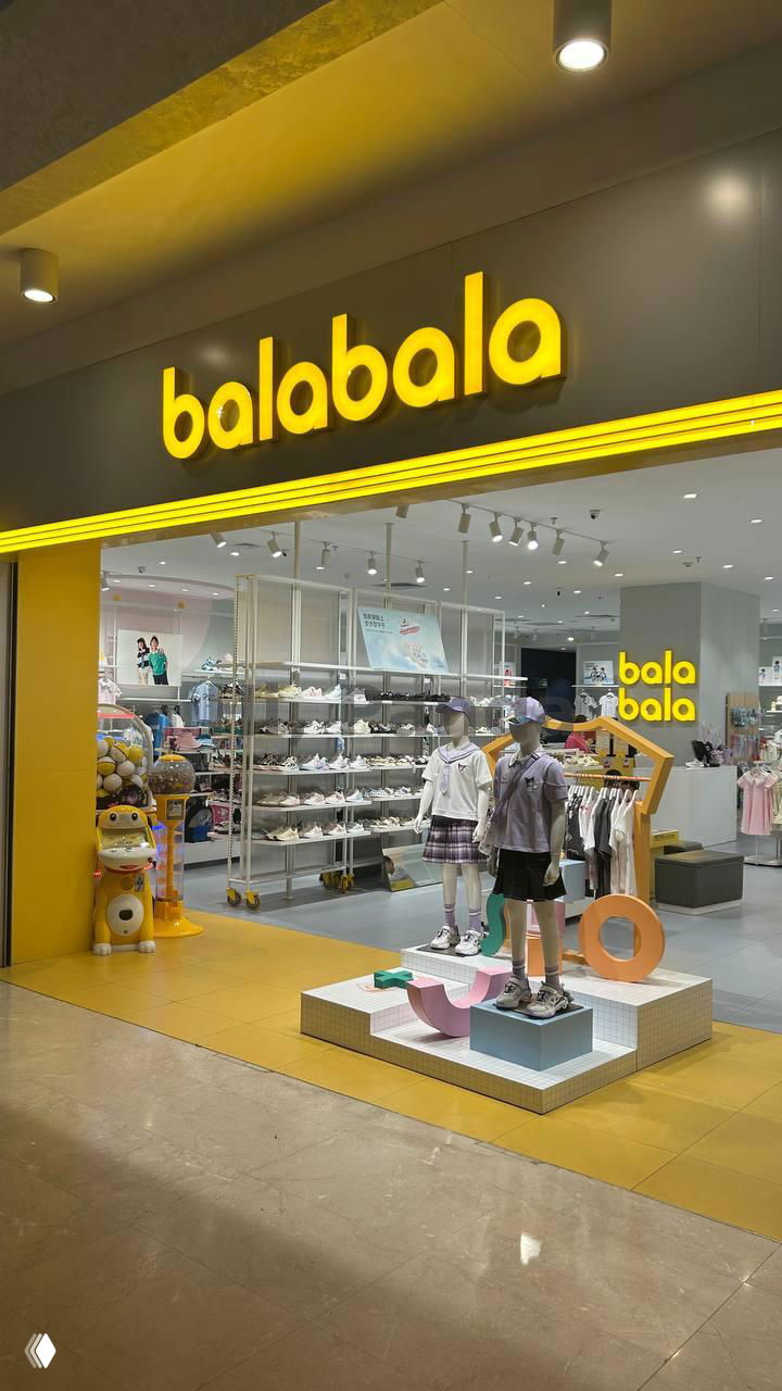 Яркая витрина детского магазина balabala в ТЦ Mangrove Tree Sanya: жёлтая вывеска, манекены в детской одежде и товары для детей на полках.