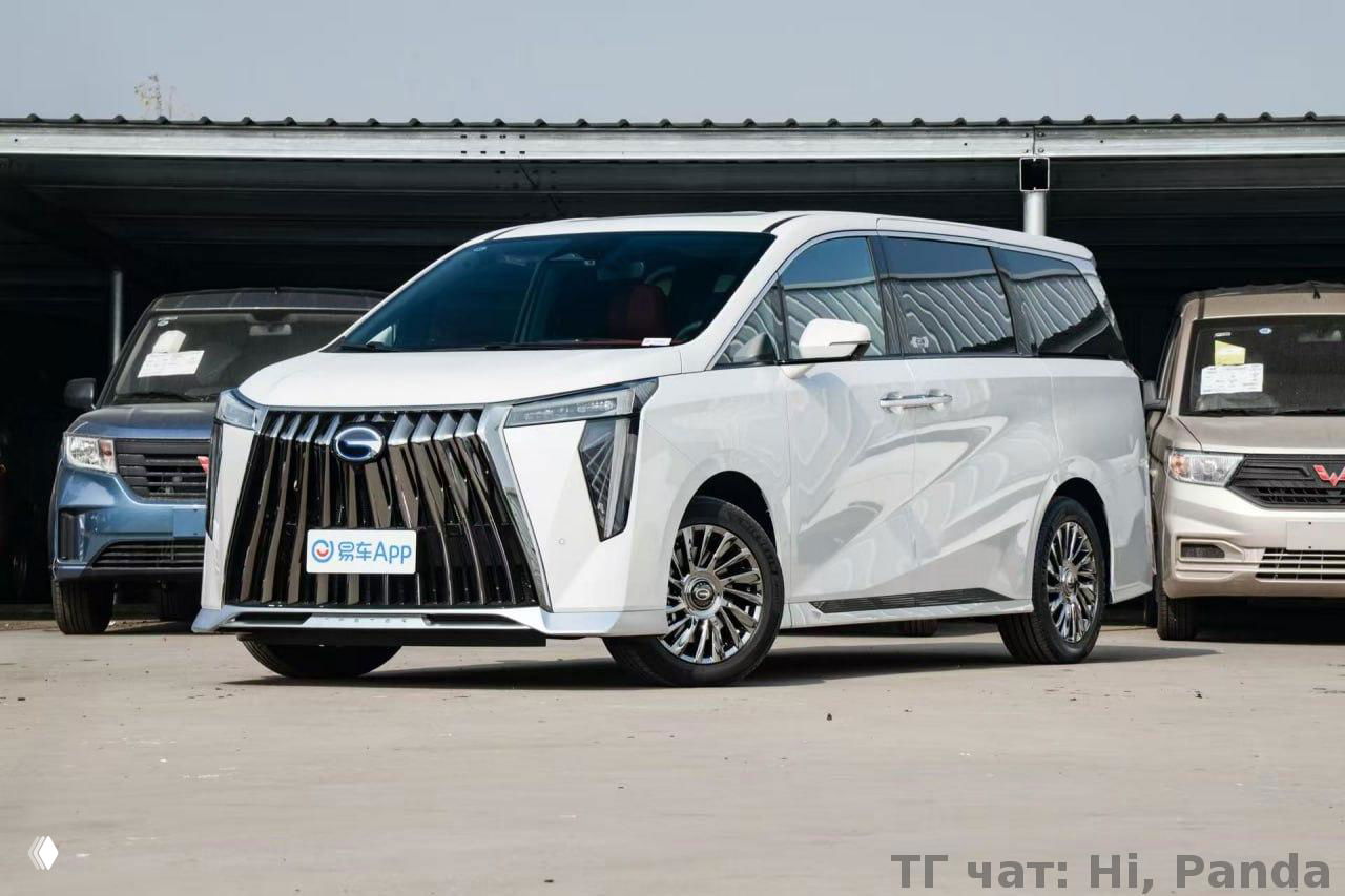 Белый минивэн представительского класса с крупной вертикальной радиаторной решёткой на площадке дилерского центра; формальный и праздничный вид кузова.