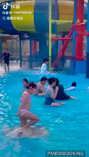 Крупный план зоны с горками и мелким бассейном: дети и взрослые играют в воде рядом с надувными и пластиковыми аттракционами, видны спасатели и персонал.