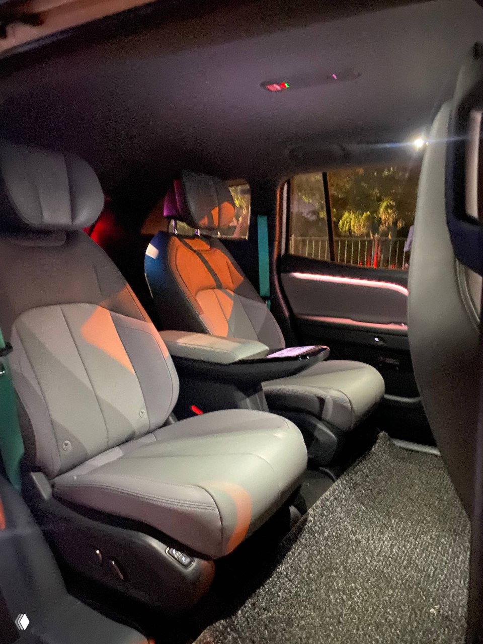 Фотография салона беспилотного автомобиля: два удобных кожаных кресла, центральный подлокотник и приглушённая цветная подсветка, демонстрирующие комфорт для пассажиров.