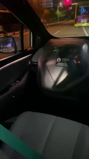 Кадр с торпедо и рулевой колонкой беспилотного автомобиля, где видно отсутствие традиционного водителя и экран центральной консоли с интерфейсом управления.