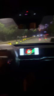 Размытый ночной кадр с видом на дорогу из салона автономного такси, видна подсветка приборной панели и городской трафик сквозь лобовое стекло.