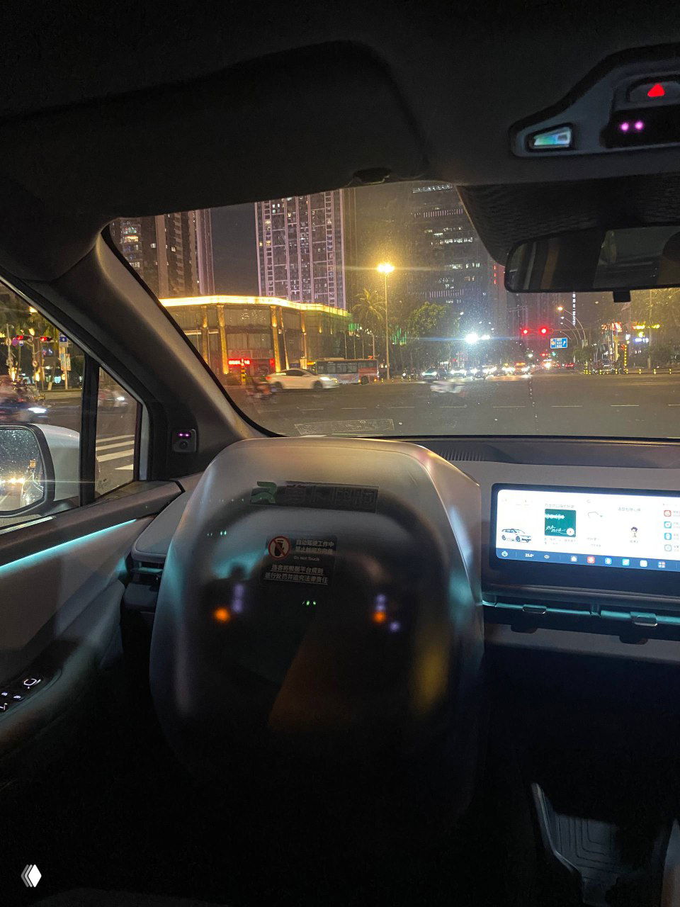 Снимок с водительской стороны на фронтальную панель и большой сенсорный дисплей мультимедиа в беспилотном автомобиле, интерфейс приложения виден на экране.