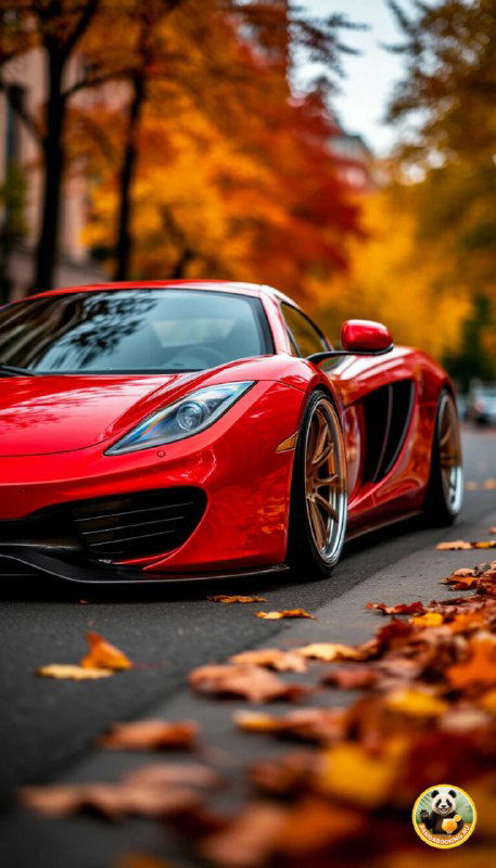 Вертикальные обои: красный спортивный автомобиль на дороге среди опавших листьев, динамичная сцена с ярким контрастом машины и тёплой осенней обстановки для телефона.