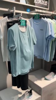 Вешалка с летними футболками и кроссовками внутри магазина 361 в Санье — показан ассортимент повседневной одежды и ценники.