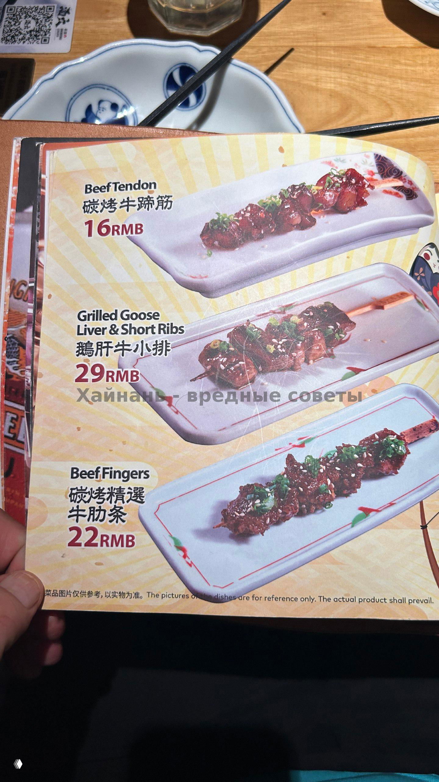 Фото разворота меню с несколькими крупными изображениями блюд и ценами, крупный план тарелок и деревянный стол в ресторане.