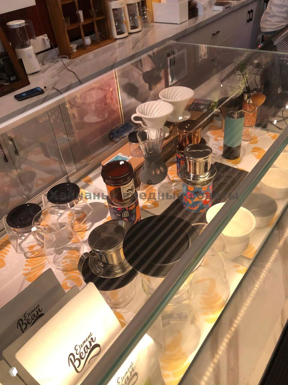 Кофейные аксессуары на витрине: пуроверы, баночки с кофе, фильтры и маленькие чашки — демонстрация инструментов для приготовления фильтр-кофе в Cozy Coffee.