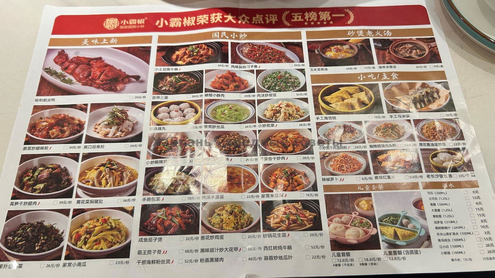 Лист меню в кафе с фотографиями множества китайских блюд и проставленными ценами — весь текст на китайском языке.