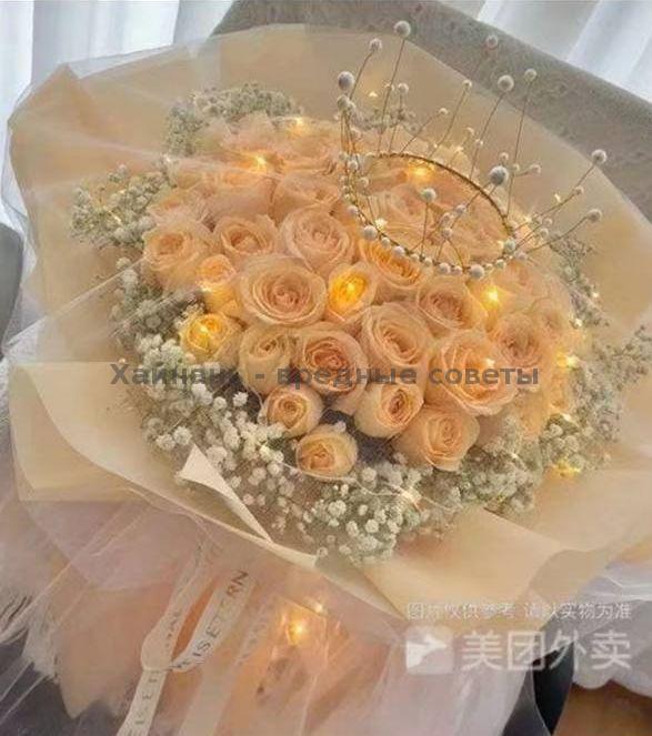 Нежный букет бежево-персиковых роз с гипсофилой и декоративной короной, оформленный в мягкую бумагу с подсветкой — стильная композиция для подарка в отель.