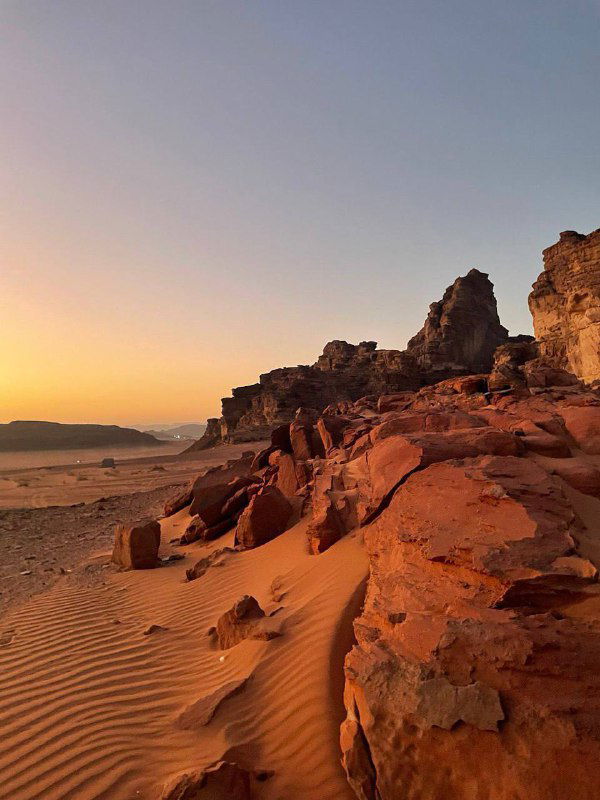 Красные песчаные дюны Вади Рам на фоне вечернего неба: ветровые формы песка и контрастные скальные выступы в пустыне.