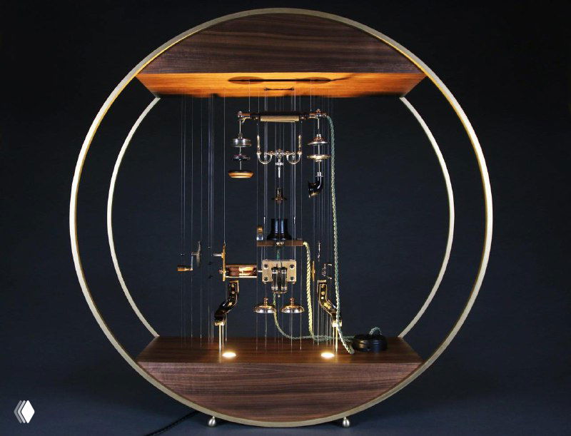 Круглая композиция-инсталляция: детали техники висят внутри деревянного кольца, тонкая подвеска и свет подчёркивают объём и конструктивность работы художника.