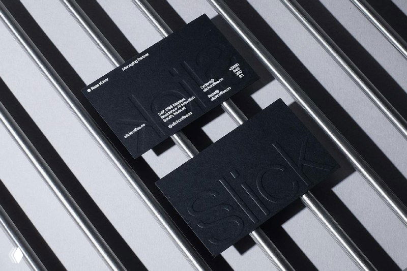 Черные визитки и тиснёный логотип Slick на металлической решётке: пример минималистичной, грубой модернистской вёрстки в полиграфии.