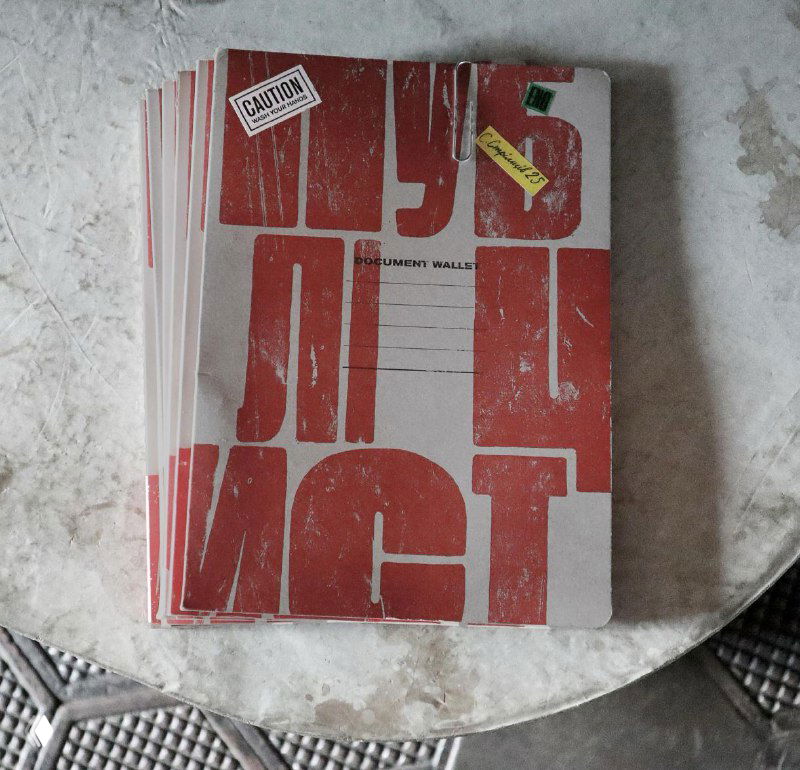 Стопка буклетов или меню с грубой красной типографикой на фактурной поверхности — примеры печатной графики в визуале ресторана.