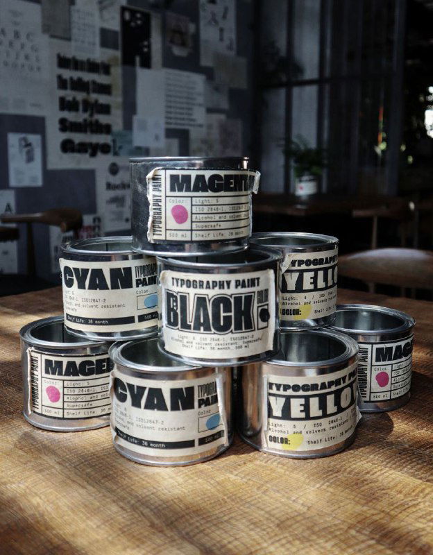 Баночки с краской для типографских работ (MAGENTA, BLACK, CYAN, YELLOW) на деревянной поверхности — отсылка к печатному процессу в айдентике.