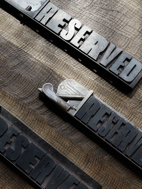 Крупный план металлических типографских буквы-матриц и форм — атрибуты печатного производства, использованные в концепции бренда.