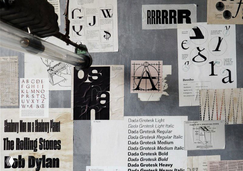 Фрагмент стены с крупными печатными отрывками, заголовками и экспериментальной типографикой, используемой в декоре и брендовых материалах.