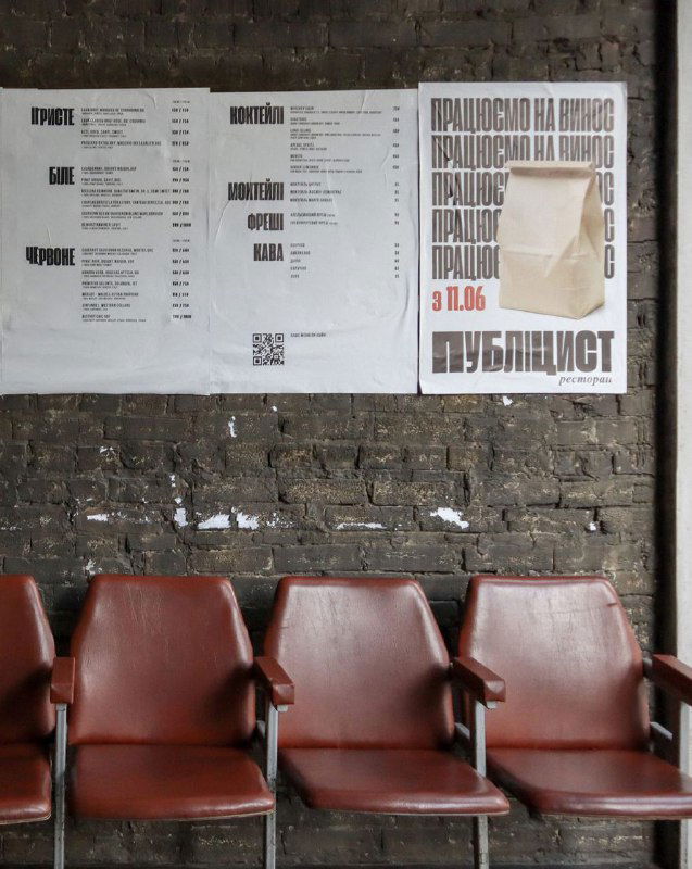 Плакат и ряд кресел в индустриальном холле ресторана, на стене листовки и меню — сочетание печатной графики и мебельного антуража.