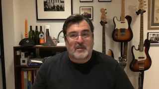 Кадр интервью: Андрей Герасимчук в домашней студии на фоне гитар, полок с книгами и предметов декора, крупный план