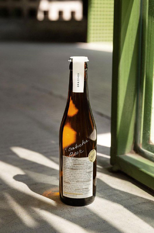 Одна бутылка Brain+er стоит на полу у зелёного окна; видно крупную текстовую этикетку с подробной информацией и аккуратный белый леттеринг на стекле.