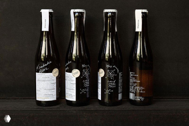 Ряд из четырёх тёмных бутылок Brain+er с развёрнутыми утилитарными этикетками на тёмном фоне — демонстрация обратной стороны упаковки и компоновки текста.