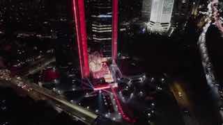 Ночной аэрофотокадр городской площади и здания с подсветкой: архитектурный контекст для постоянной инсталляции в штаб-квартире банка.