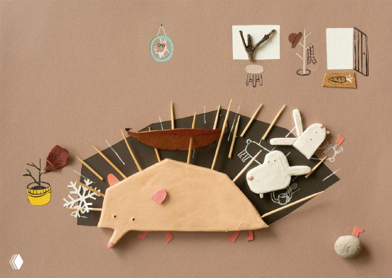 Композиция-поделка с ежом и другими фигурками, объекты из картона и ткани, видна ручная сборка и акцент на тактильных текстурах для детской книги.