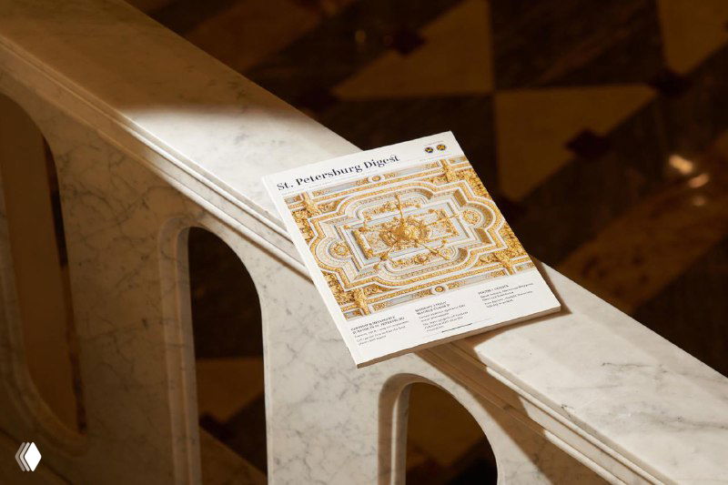 Листовка или отрывной фрагмент из выпуска St. Petersburg Digest на мраморном парапете: детализированная орнаментальная графика и тёплый интерьерный контекст.