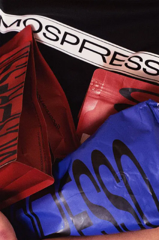 Набор разноцветных пакетов Mospresso — красные и синие упаковки с крупной типографией; кадр демонстрирует повторяемый брендовый паттерн и фактуру материалов.