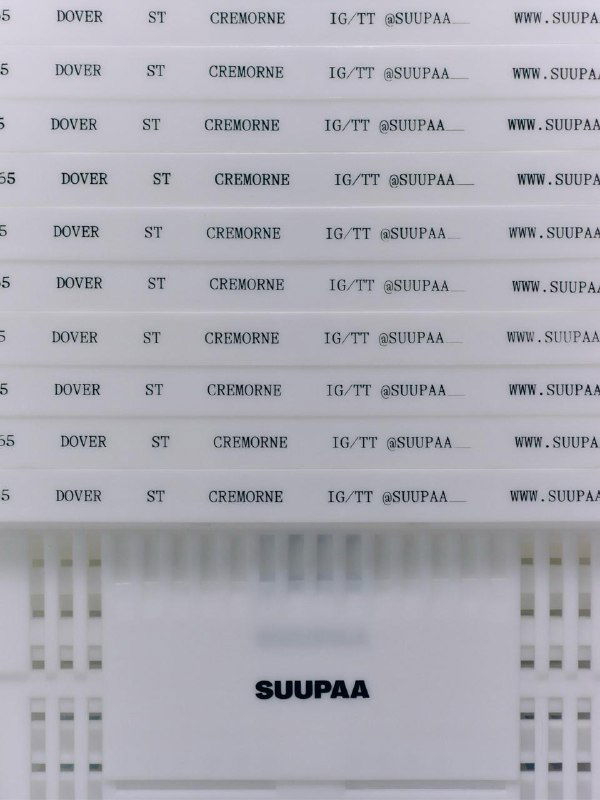 Деталь брендовых материалов Suupaa: повторяющийся текст и сетка штриховок на упаковке и носителях, единая типографика и монохромная подача элементов.