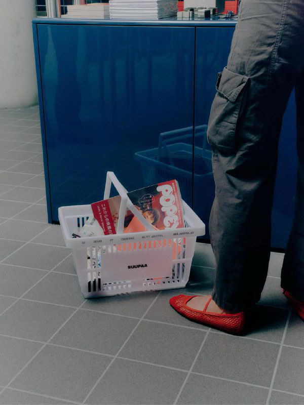 Покупатель с пластиковым корзинным контейнером Suupaa: корзина с продуктами, логотип на коробке и визуализация практического применения бренд-элементов в магазине.