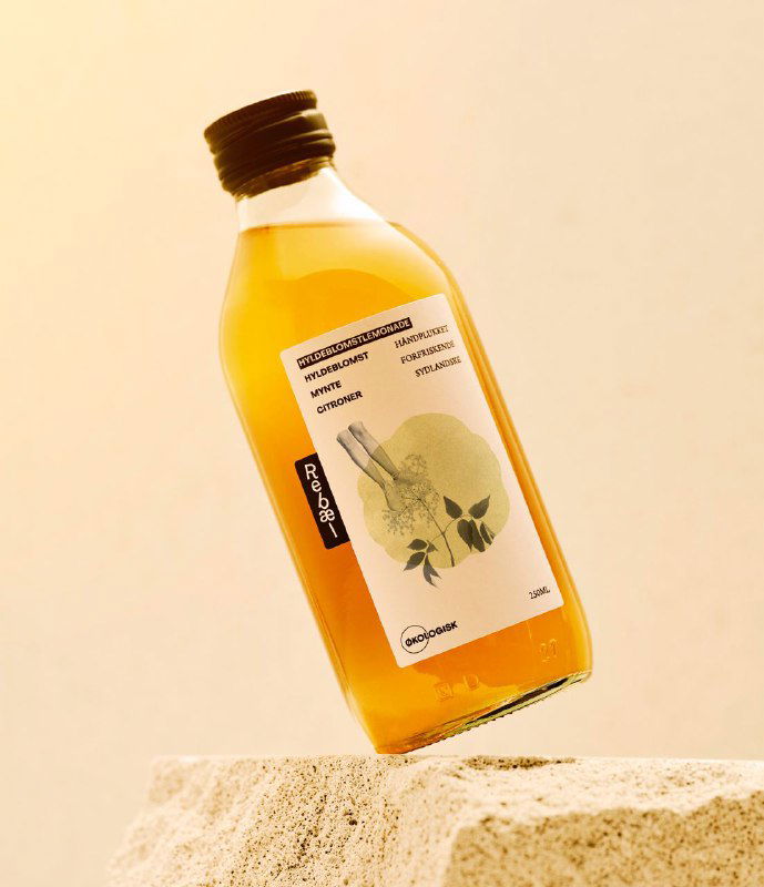 Вертикальный ракурс: бутылка Rebæl со наклеенной этикеткой, минимальная цветовая палитра и графика, демонстрирующие стиль бренда.