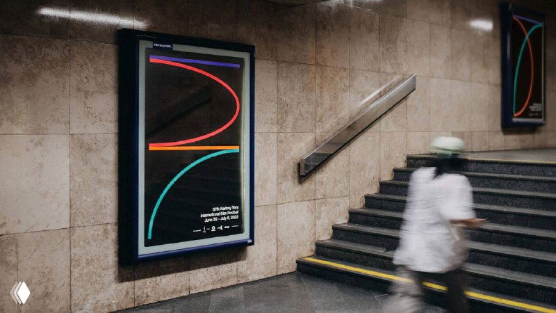 Фотография станции или подземного перехода с рекламными постерами, демонстрирующими логотип и графику 57-го Karlovy Vary International Film Festival в городской среде.