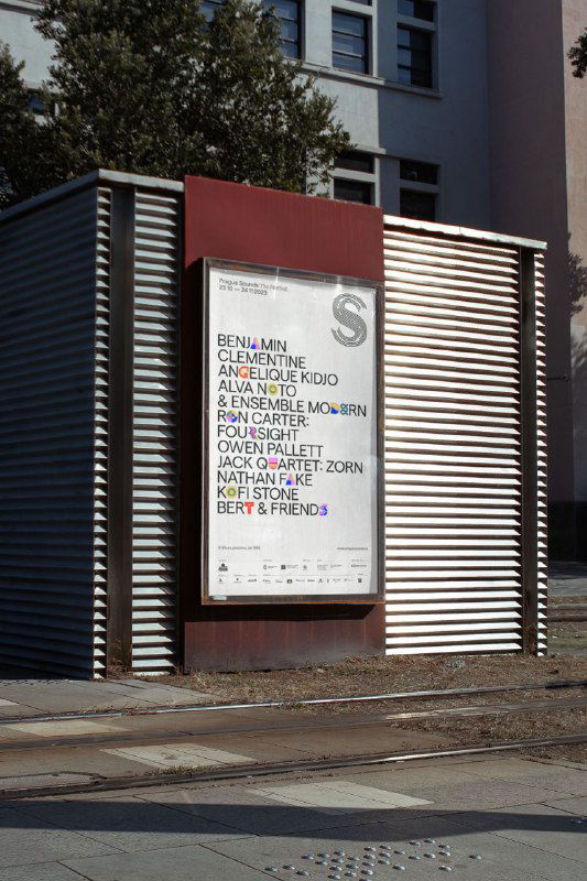 Рекламный щит у здания с вертикальным макетом афиши: лаконичная верстка, перечень исполнителей и элементы фирменной айдентики в урбанистическом окружении.