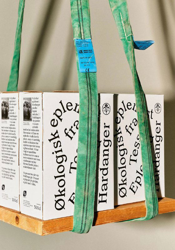 Вертикальная фотография упаковок Tessas Eplegard на поддоне, крупный план печатной типографики и боковые яркие этикетки с информацией о продукте.