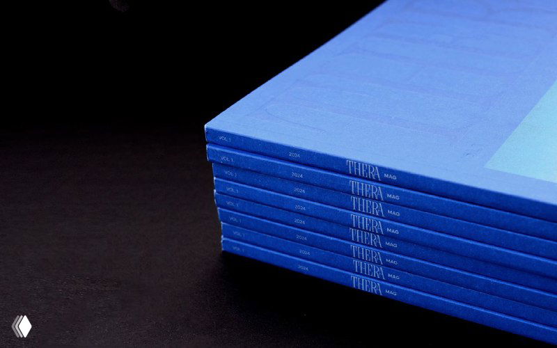 Стопка синих журналов Thera Mag, виден срез переплёта и аккуратная полиграфическая отделка — подчёркнутое тиснение на каждом экземпляре.