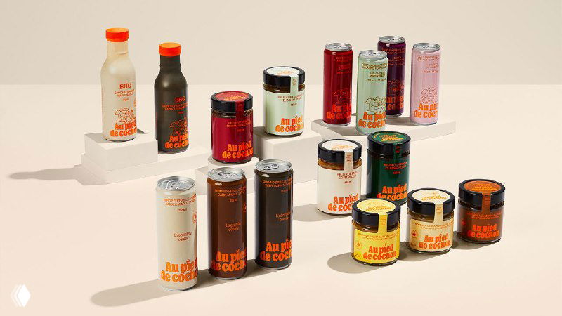 Коллекция упаковок: банки, тубы и банки с этикетками в ретро-стиле, расставленные на белой поверхности для презентации продуктовой линейки Au Pied de Cochon.