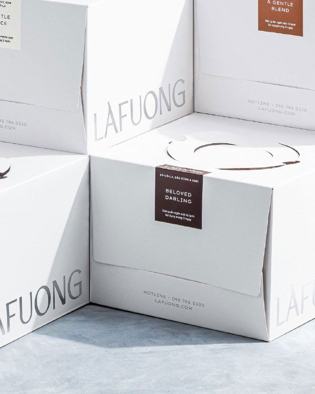 Крупный план стыка белых коробок LaFuong с акцентом на тисненую типографику и маленькие этикетки с информацией о продукте и вкусе.