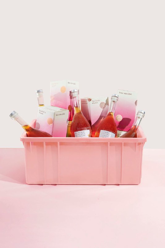 Пластиковый ящик цвета пудрового розового, заполненный несколькими бутылками Phung Thi и упаковками: акцент на цветовые переходы и праздничную атмосферу в кадре.
