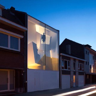 Прозрачный фасад жилого здания с инсталляцией света внутри — пример интеграции художественной экспозиции и городской архитектуры вечером.