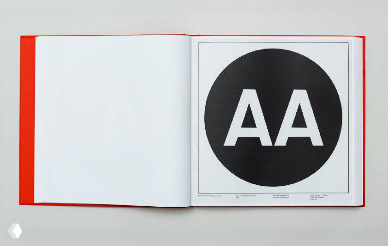 Разворот книги с крупным чёрным кругом и белыми буквами «AA», пример контрастной графики из издания стандартов NYCTA.