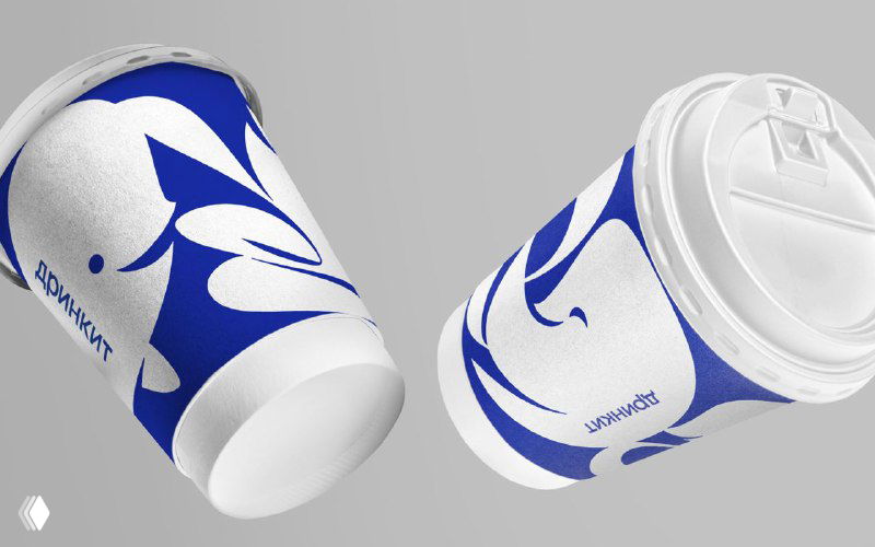 Макет бумажных кофейных стаканов с крупным абстрактным синим рисунком и логотипом‑эмоджи, ракурс демонстрирует применение орнамента на упаковке.