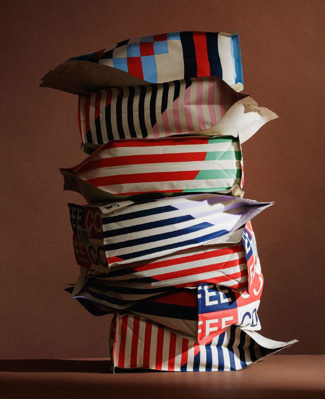 Стопка мягких пакетов с яркими полосатыми и геометрическими боковыми панелями; акцент на текстуре упаковки и взаимодействии цветов.