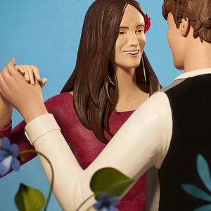 Глиняные фигурки танцующей пары: стилизованные формы, яркая одежда и декоративные детали на фоне простого нейтрального фона, аккуратная ручная лепка